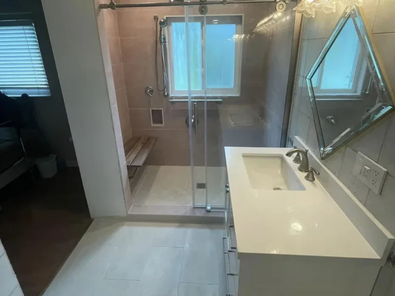 The same bathroom with a glass walk-in shower, a white vanity, and the same diamond mirror.