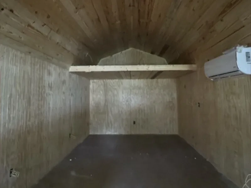 A wood loft shelf under a plank ceiling, with a wall-mounted air conditioner on the right wall.