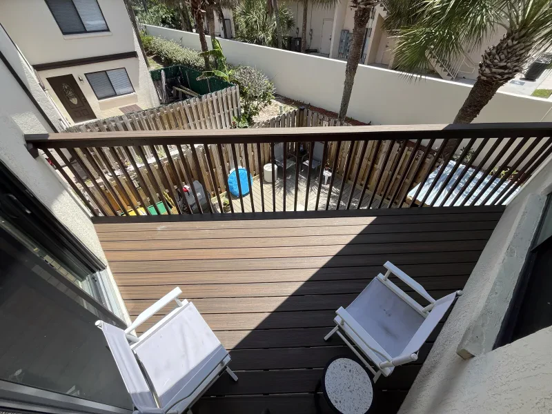 The same balcony deck refinished with a warm wood-look finish, seen from above.