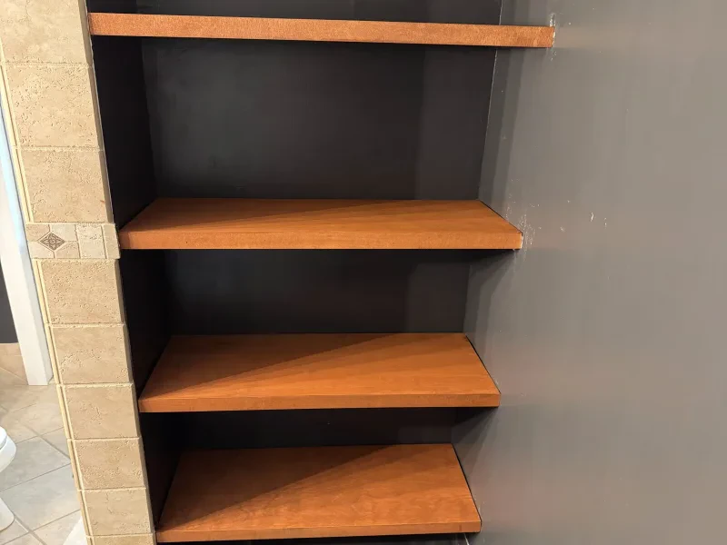 The same niche with four wood shelves beside the same tile column.